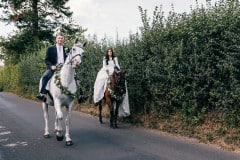 Bride and Groom riding their horses to their wedding reception