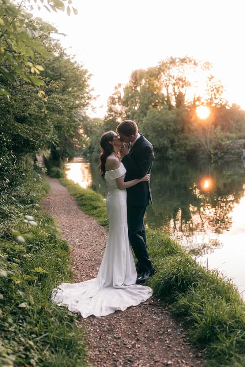 Romantic couple embracing on a riverside path during sunset, capturing love and intimacy in natural.