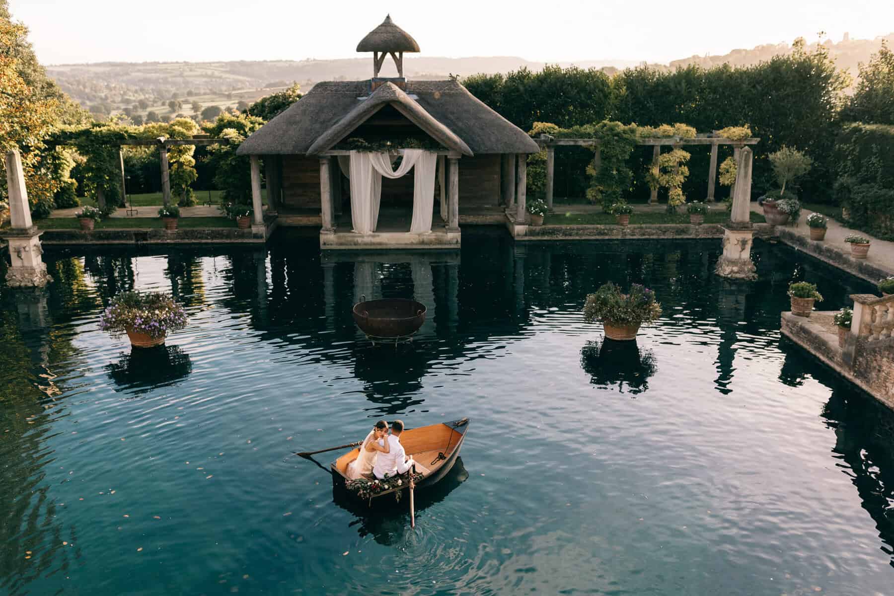 Romantic outdoor wedding scene with a couple in a boat on a beautiful pool surrounded by lush greene at Euridge Manor.